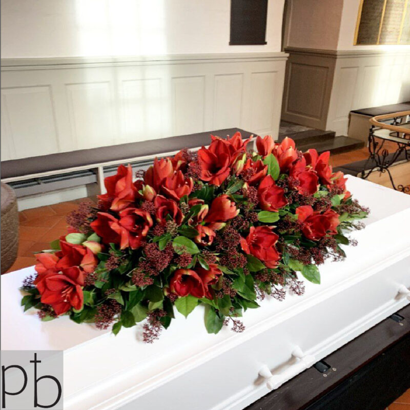 Erfaren lokal florist binder bårebuket med hvide roser og grønt til begravelse