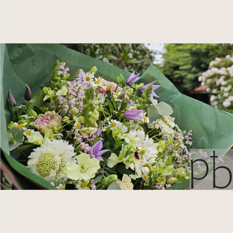 Hjerteformet sorgkrans med hvide liljer, roser og eukalyptus bundet med silkebånd klar til begravelse i Farum (3520)