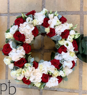 Hjerteformet sorgkrans med hvide liljer, roser og eukalyptus bundet med silkebånd klar til begravelse i Farum (3520)