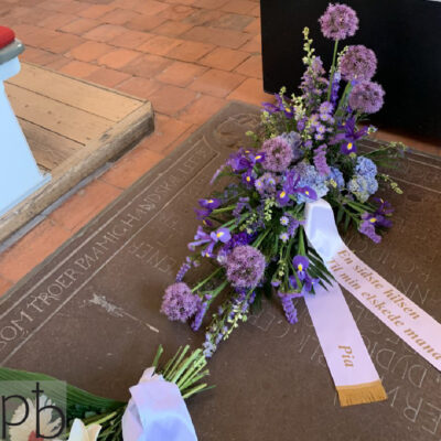 Erfaren begravelsesblomster florist binder håndbundne bårebuketter og kranse med silkebåndstekst til ceremonier i Charlottenlund postnummer 2920