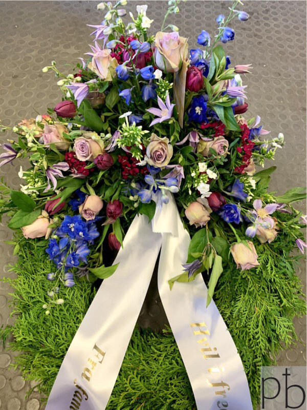 Krans til begravelse Holte – rund blomsterkrans i afdæmpede toner med personligt bånd, bundet af ParadisBlomster til en værdig afsked.