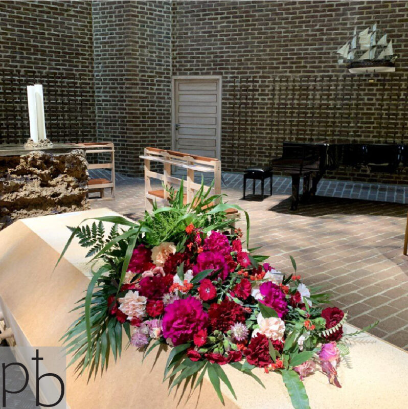 Værdig båredekoration i hvid og grøn med eucalyptus, leveret planlagt og præcist til kirke i Greve